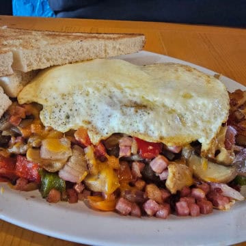 egg and ham hash on a white plate with toast