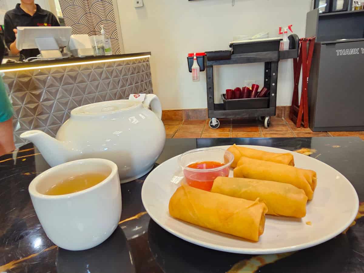 egg rolls and a pot of tea and cup on the table