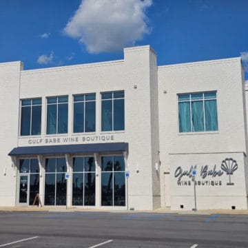 Gulf Babe Wine Boutique sign with wine glass on the side of a white brick building