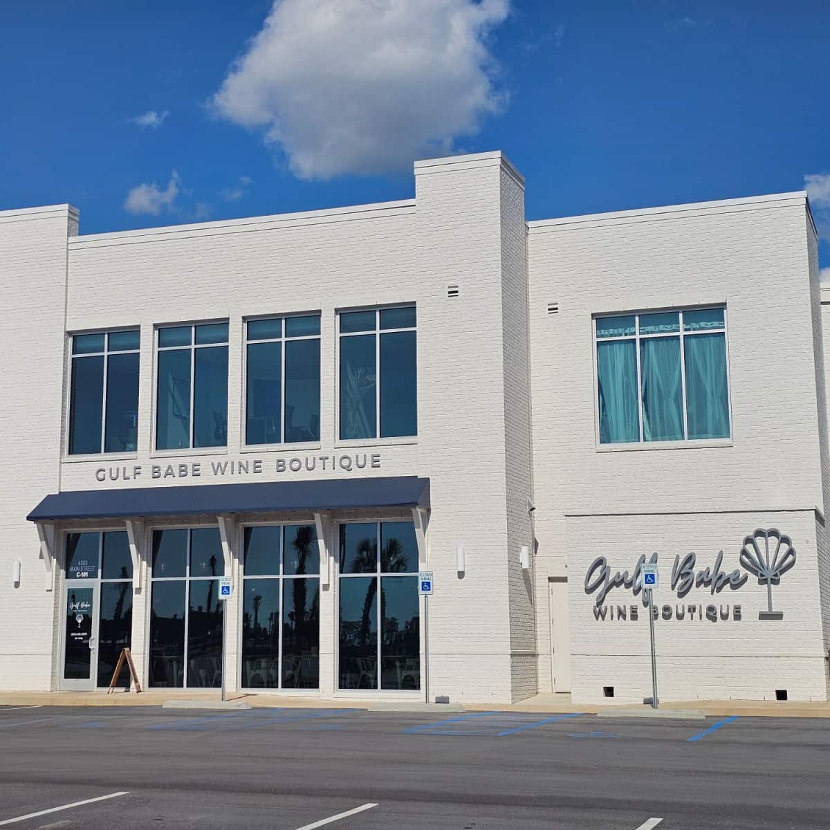 Gulf Babe Wine Boutique sign with wine glass on the side of a white brick building