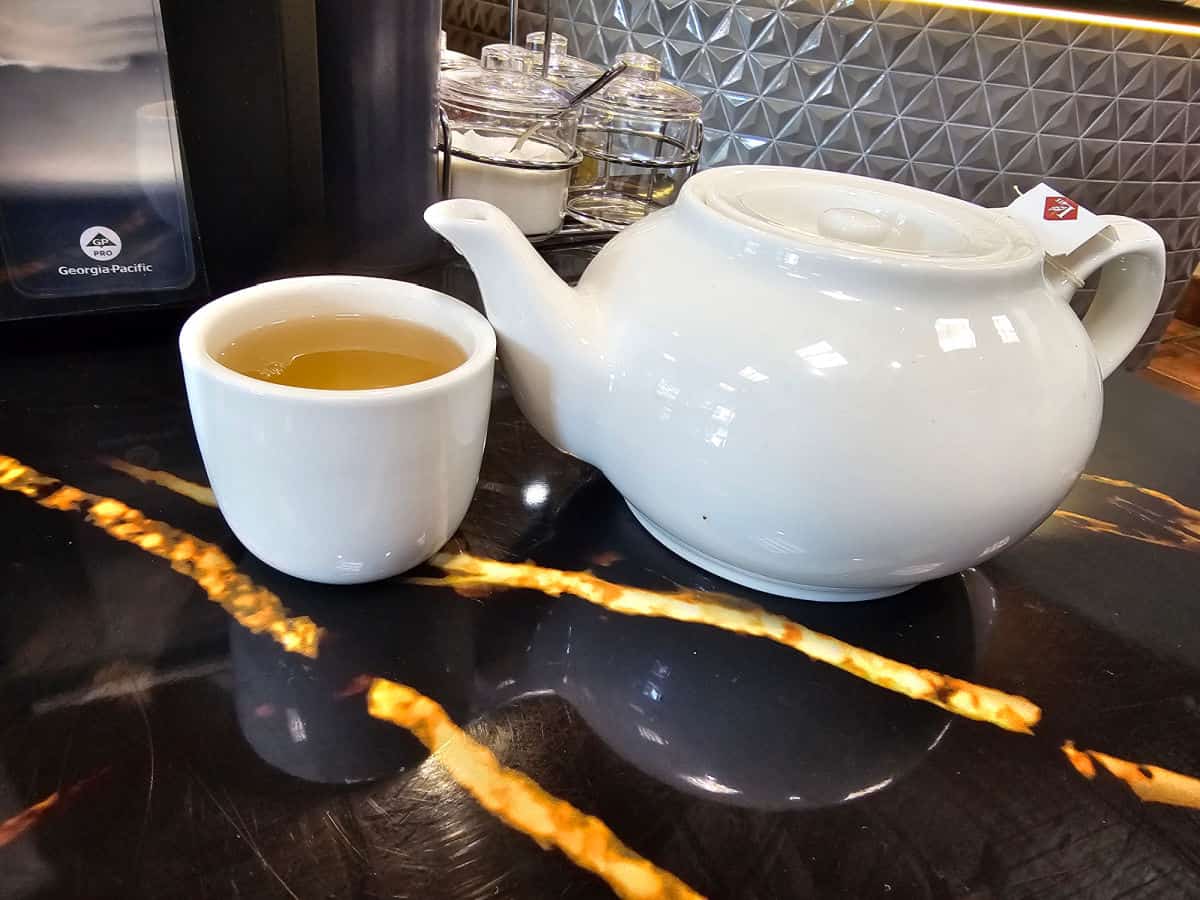 white tea pot next to a glass of tea