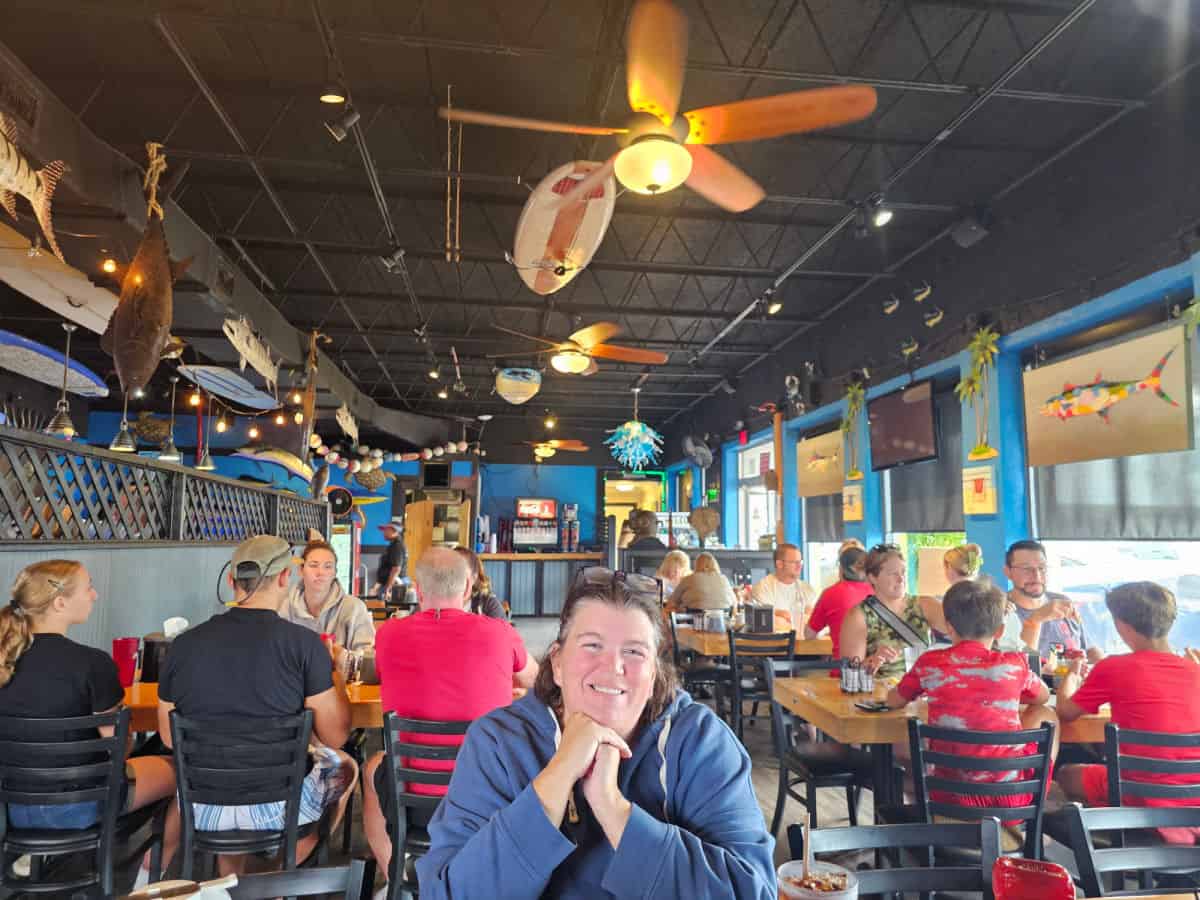 Tammilee sitting in Coconuts Bar & Grill with people at tables behind her