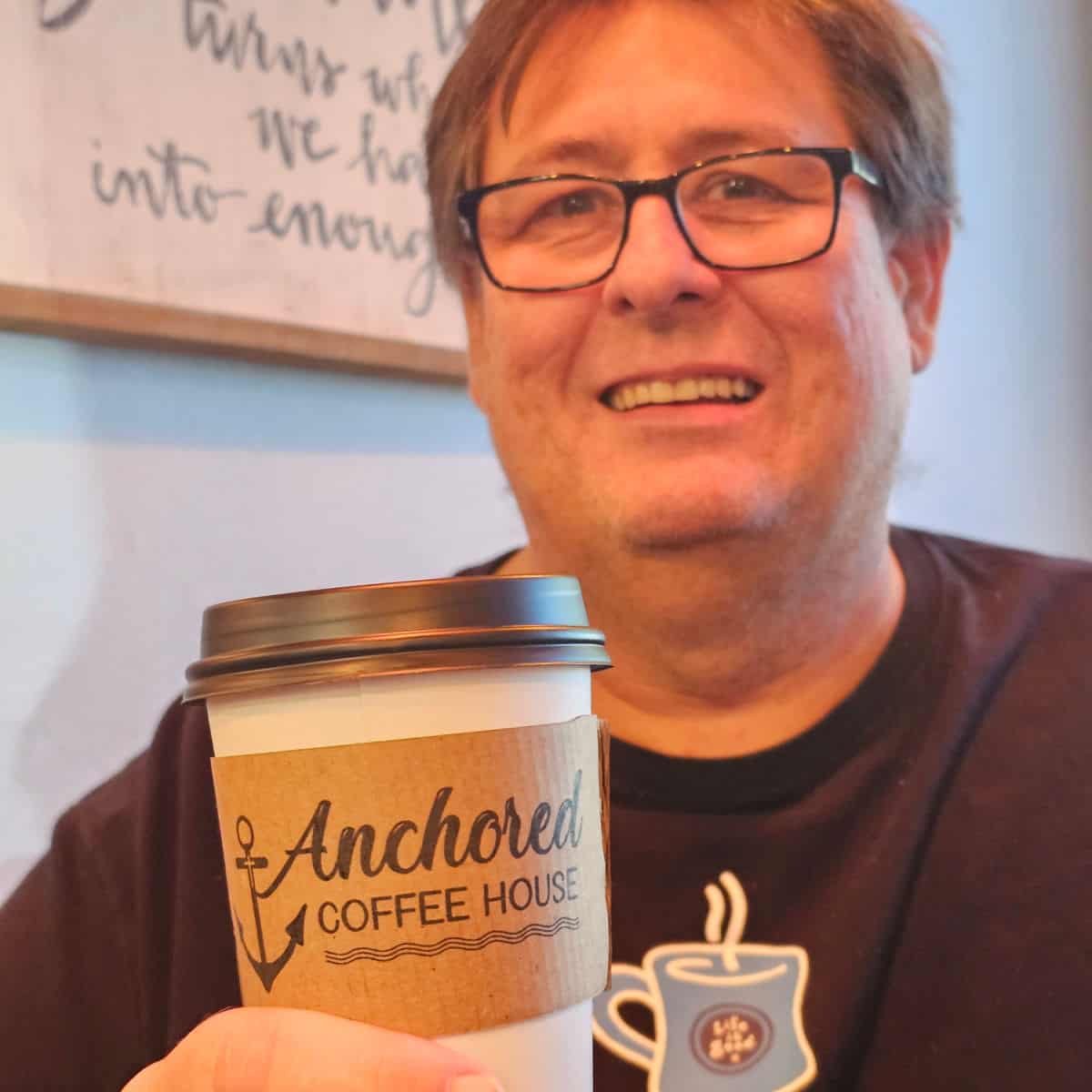 John holding an Anchored Coffee House cup