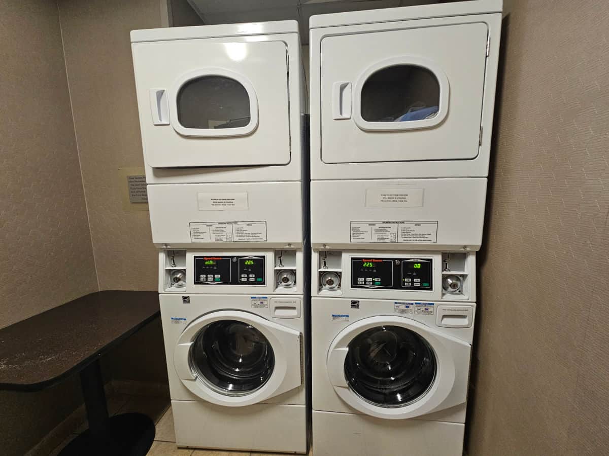 stacked white washer and dryers with a table next to it