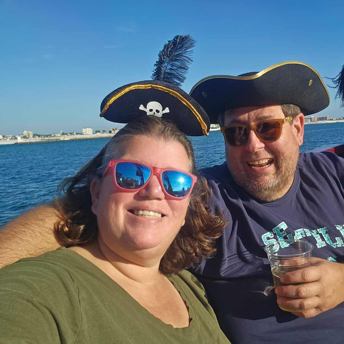 Tammilee and John wearing pirates hats with the Gulf behind them on the Buccaneer Pirate Cruise, Destin