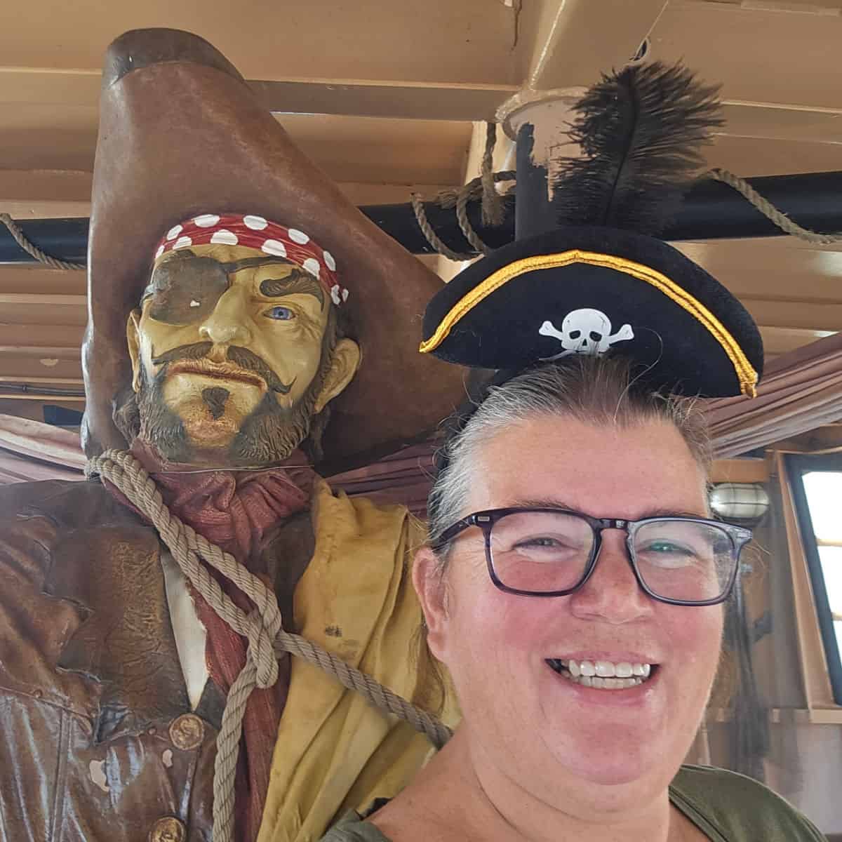 Tammilee wearing a pirate hat next to a pirate statues