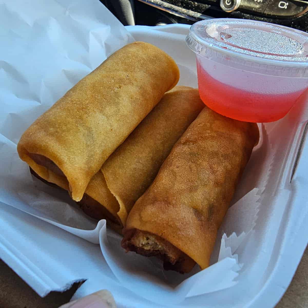 vegetable spring rolls in a to go container with a container of sauce