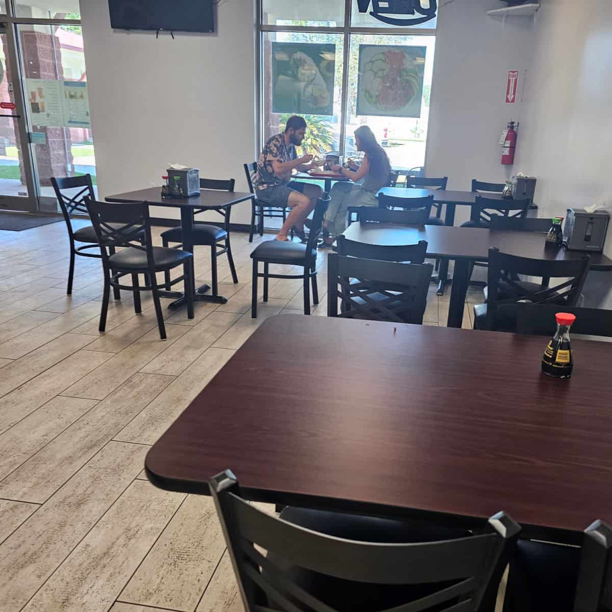 poke bowl sushi burrito & boba indoor seating with tables and chairs, a couple sitting next to the window