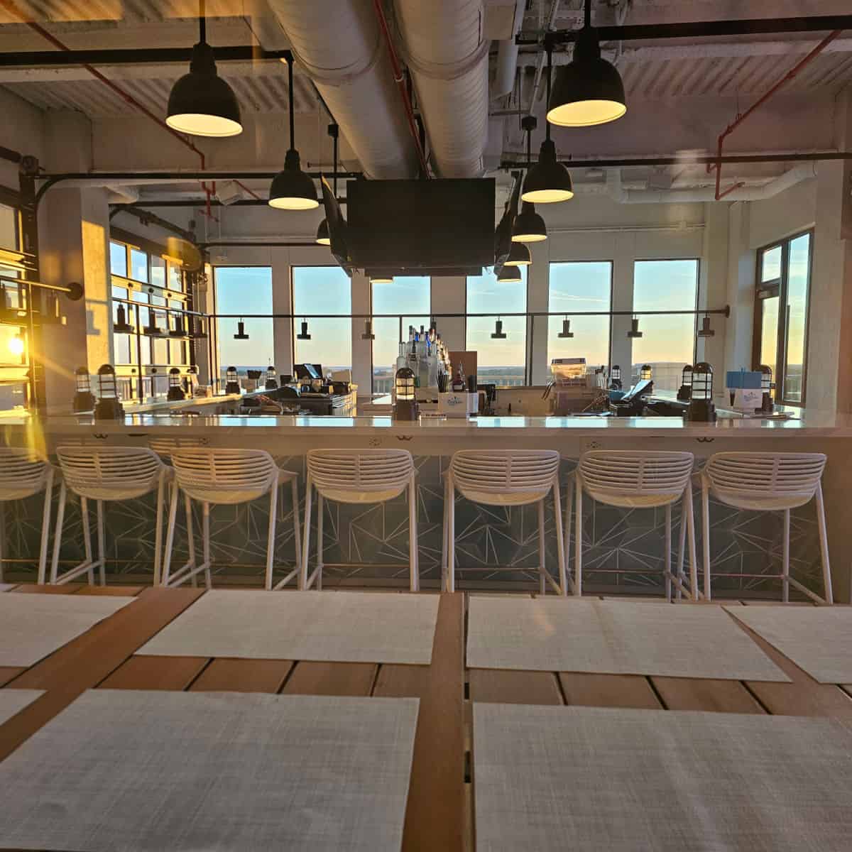 Ara pool bar with white chairs next to the bar sunlight streaming in over the bar