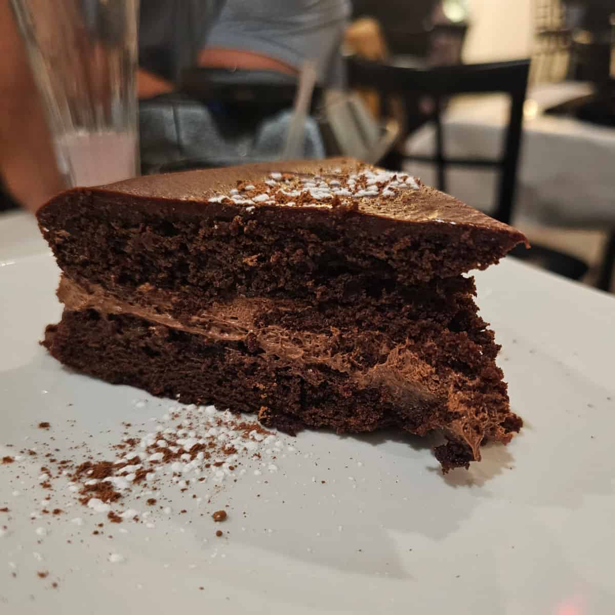 Chocolate torta on a white plate with a cocktail behind it at Fresco in Bon Secour