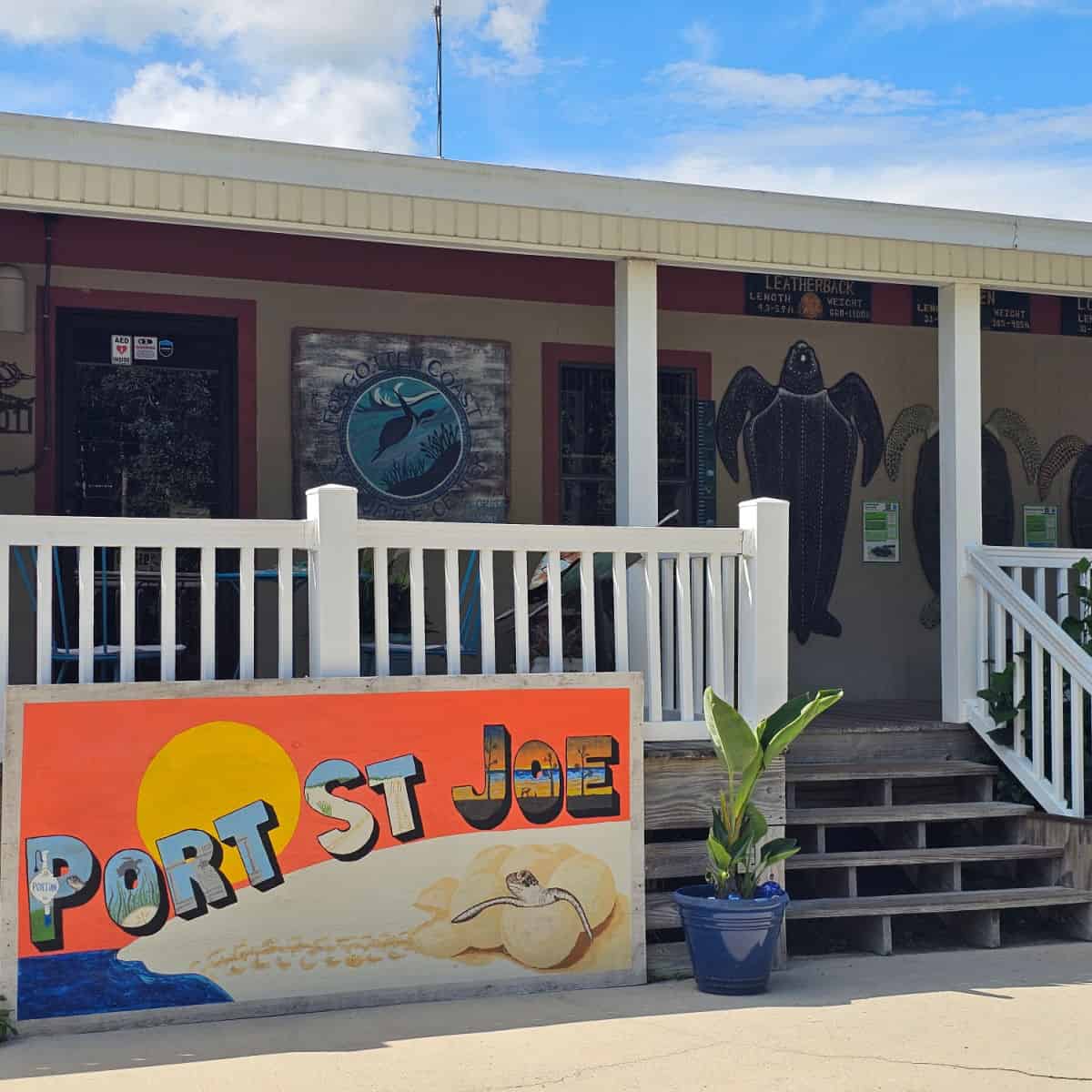 Port St. Joe sign with a turtle coming out of an egg, near the steps up to the Forgotten Coast Sea Turtle Center with turtles on the wall