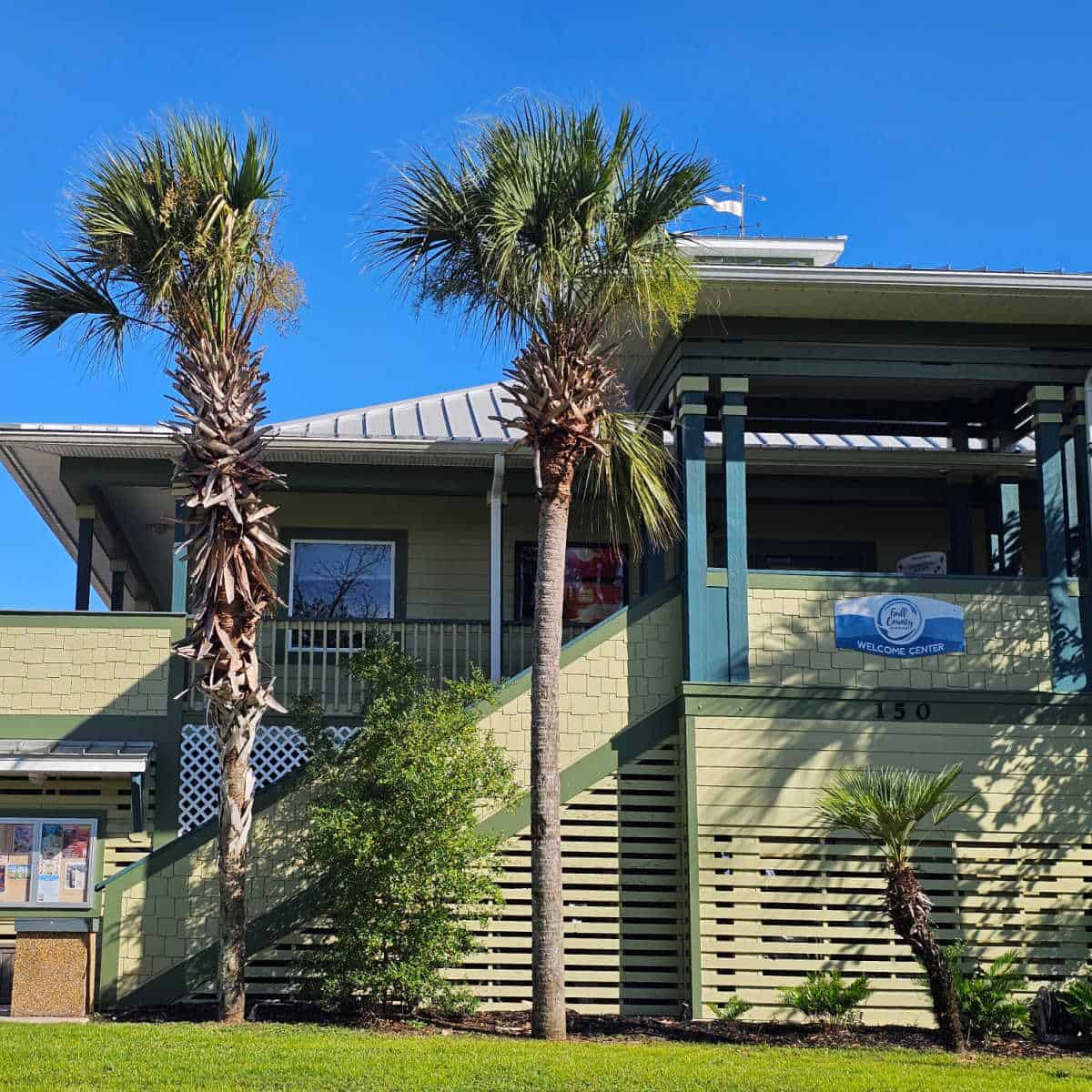green building with palm trees, Gulf County Welcome Center sign on the side of the building