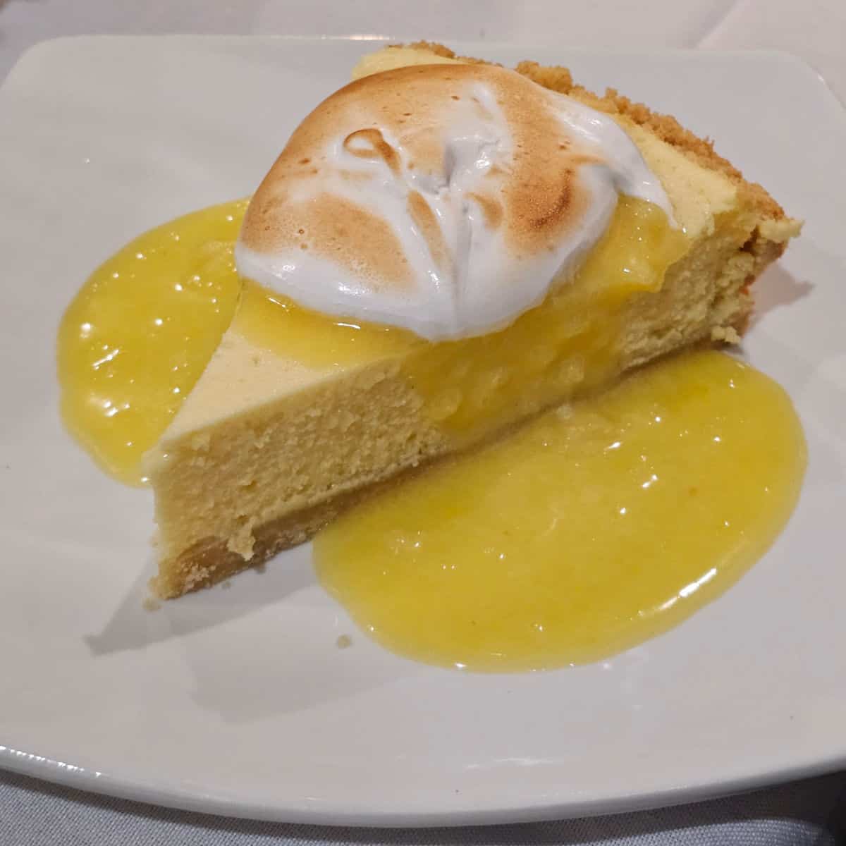 Limoncello Merinque Pie on a white plate with lemon glaze
