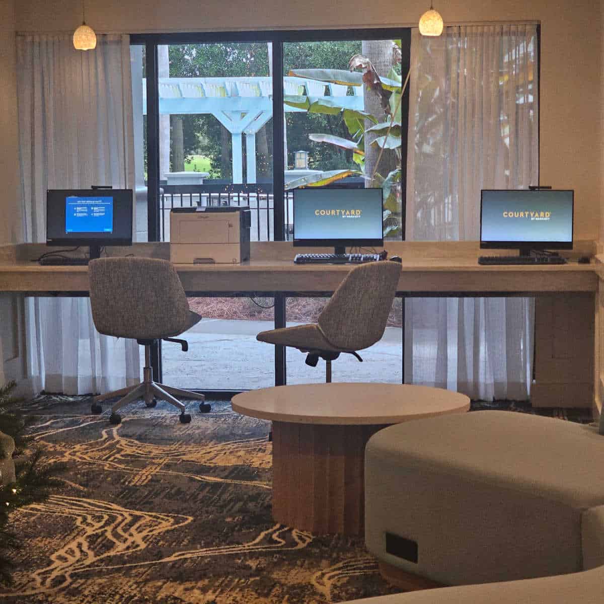 Courtyard Sandestin work area with three computers and chairs, window view of the pool.