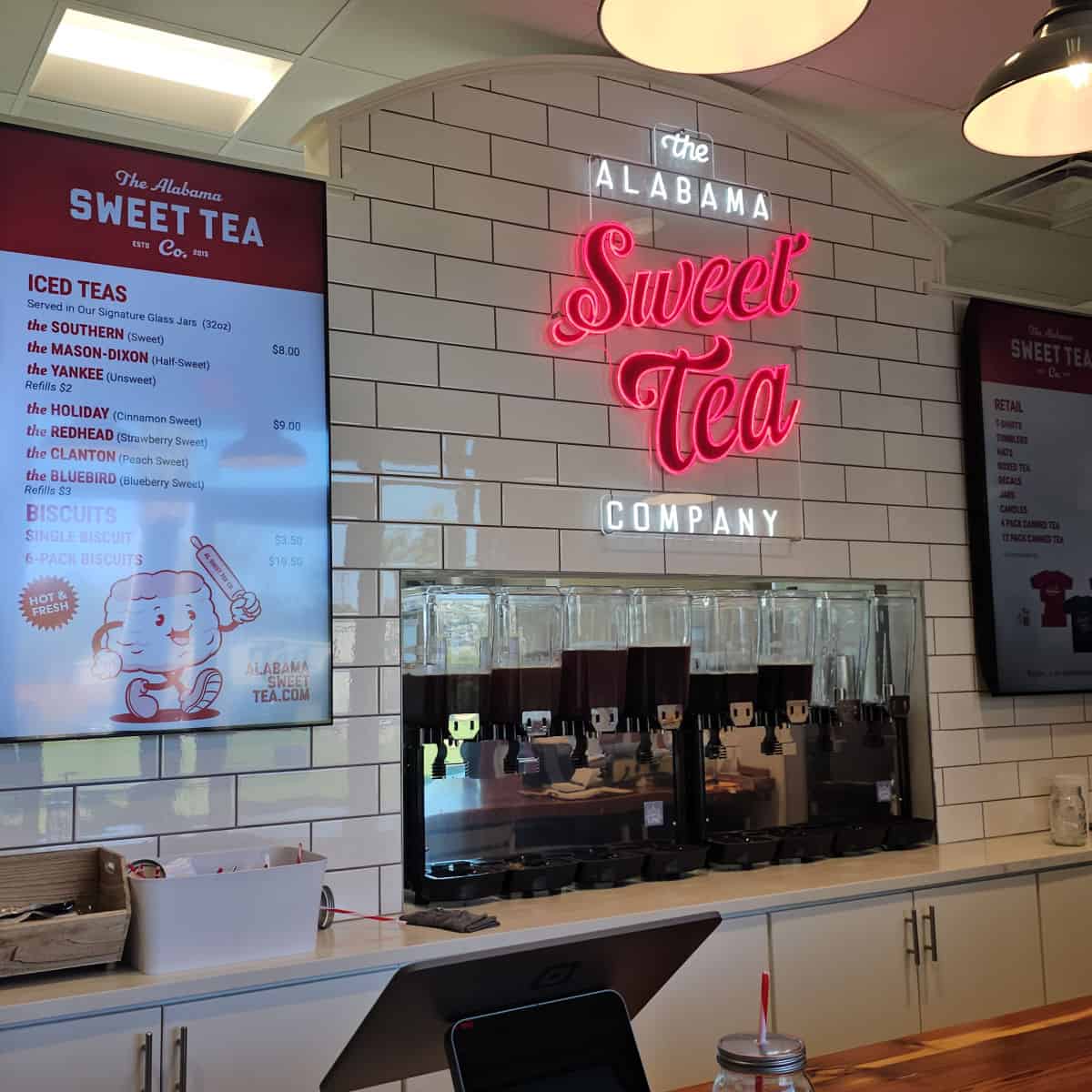 The Alabama Sweet Tea Company neon light on the back wall with drink dispensers below and the menu on the wall