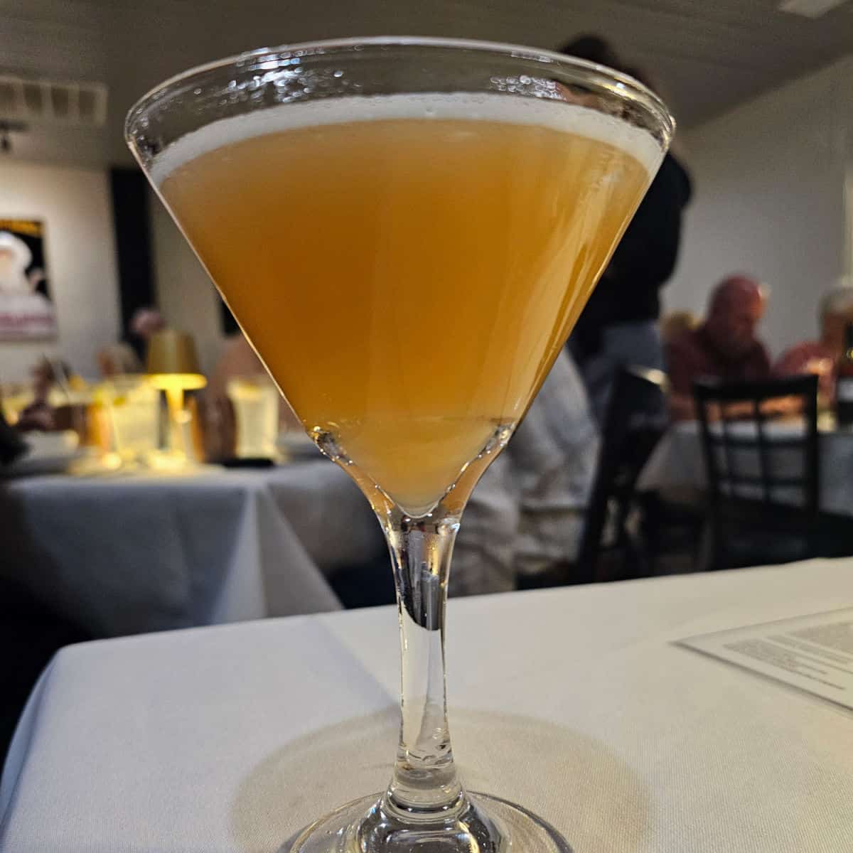 Sidecar cocktail in a martini glass on a white tablecloth in Fresco in Bon Secour restaurant with people dining in the background