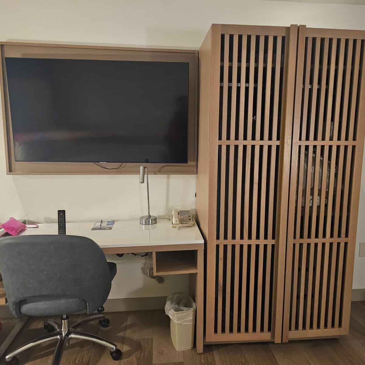 Courtyard Sandestin hotel room with a desk, chair, flatscreen tv over the desk, and a wood slat storage cabinet