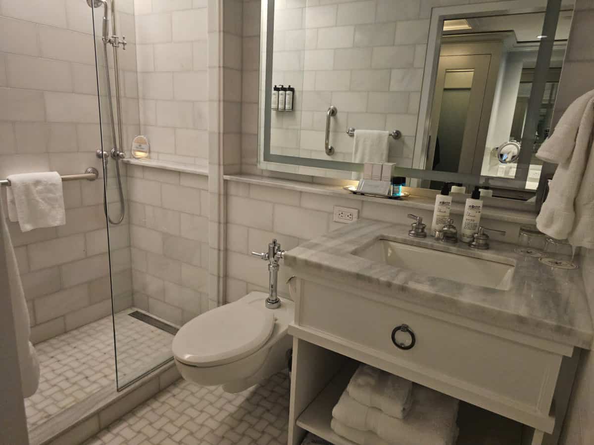 Marble tiled bathroom with sink, toilet, and walk in shower