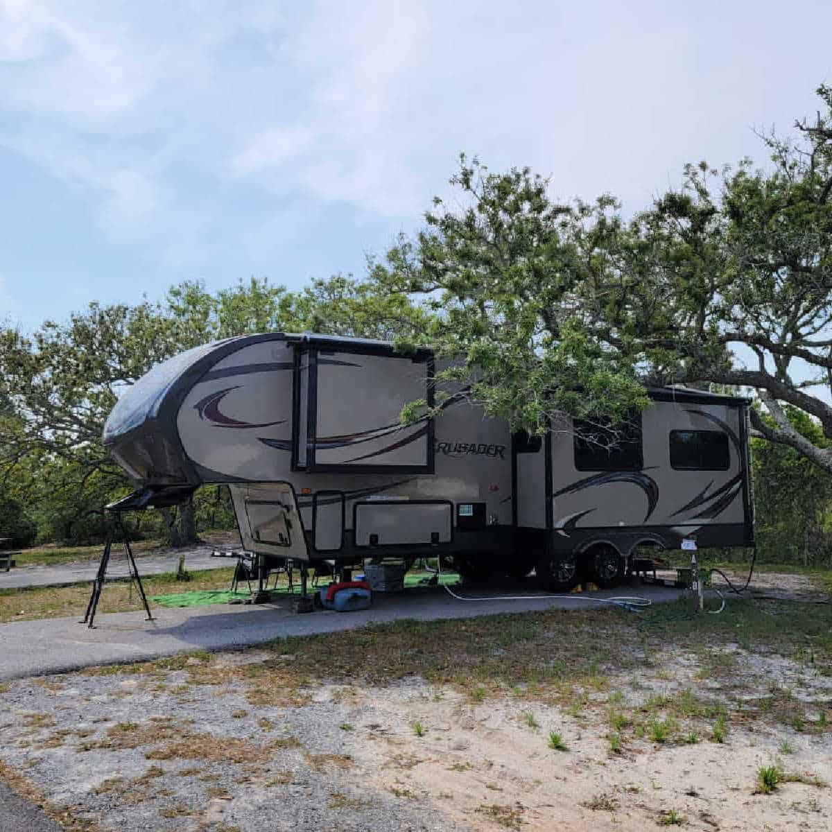 RV in a campsite at Fort Pickens Campground with trees around it