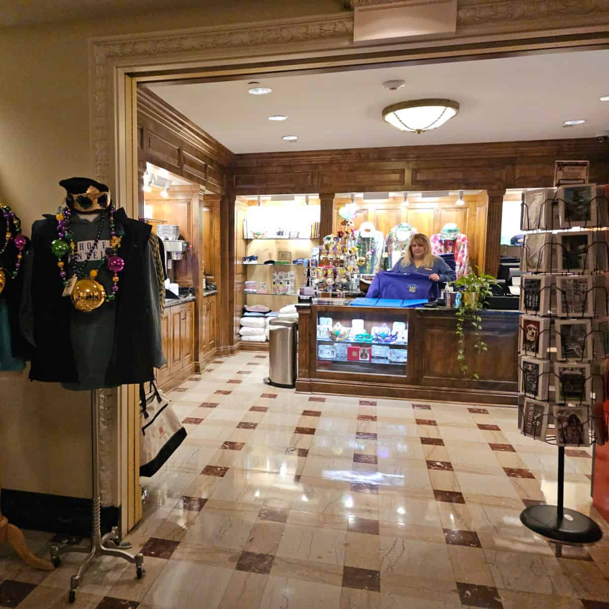 Hotel montleone gift shop with cards, employee folwing a shirt, t-shirt display with mardi gras beads