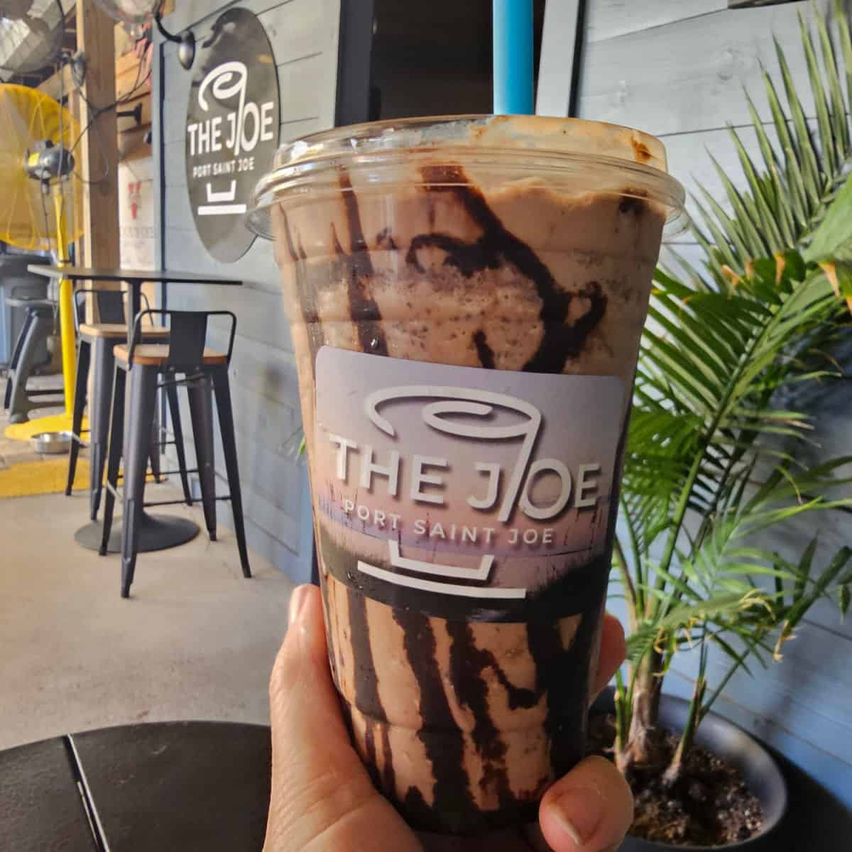 hand holding an iced coffee with chocolate swirls at The Joe Port Saint Joe