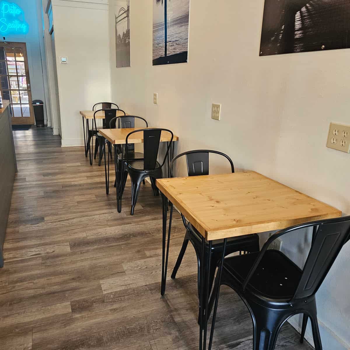 Indoor seating at The Joe Port St Joe with tables for 2 people, black chairs, and electrical plugs above the tables