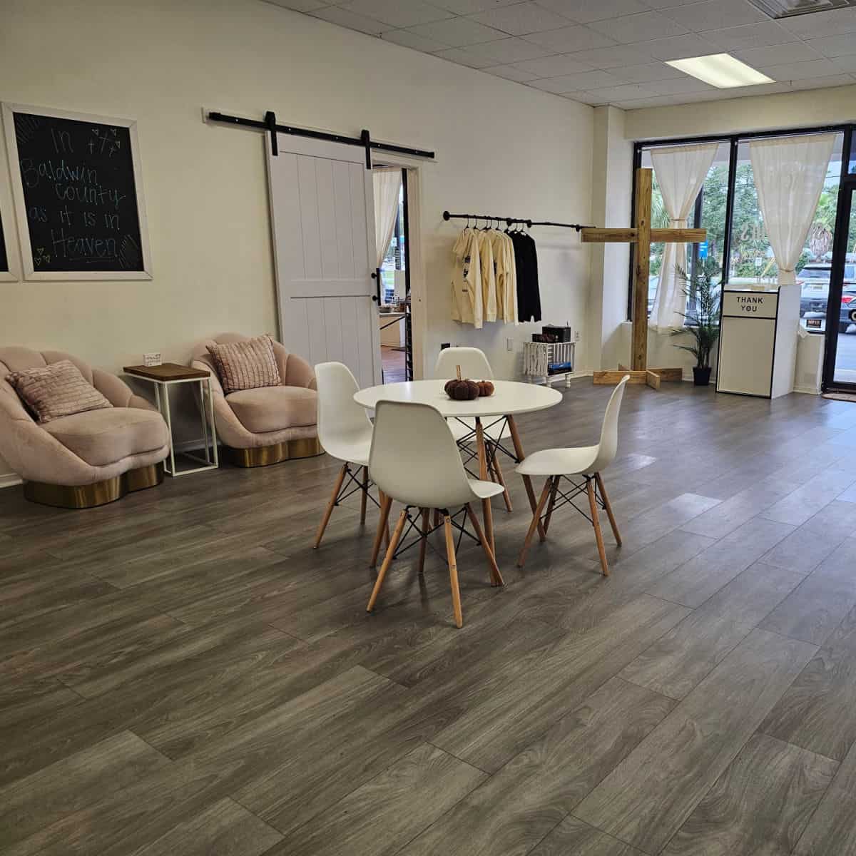 indoor seating with a table and 4 chairs, pink chairs against the wall, a large wooden cross, garbage can