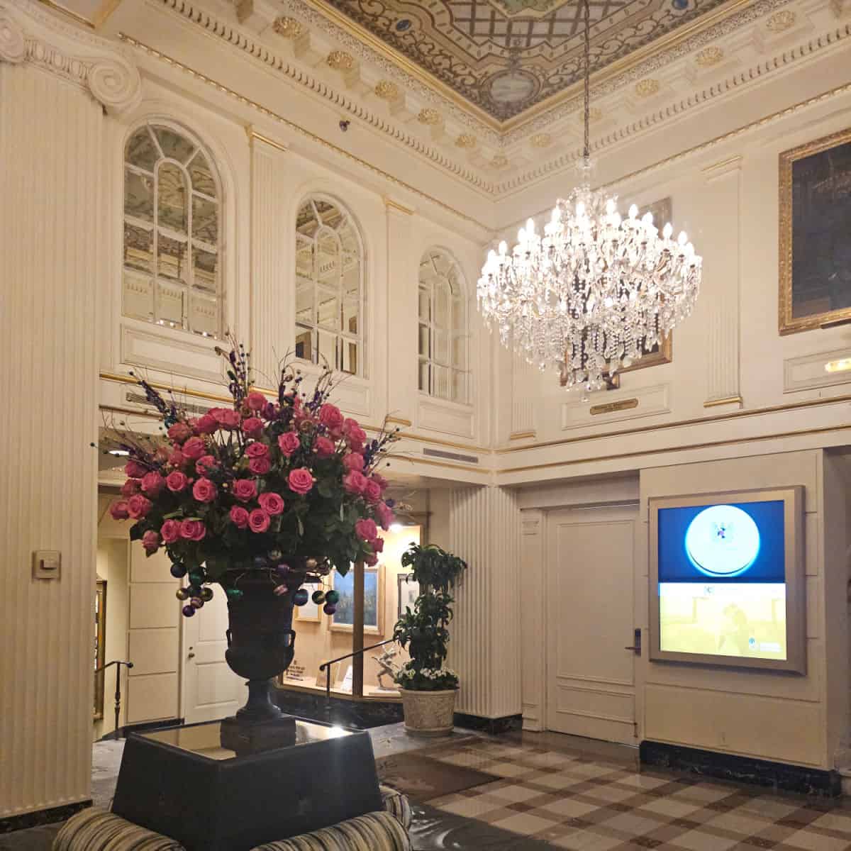 Elegant hotel lobby with a large floral arrangement and chandelier.