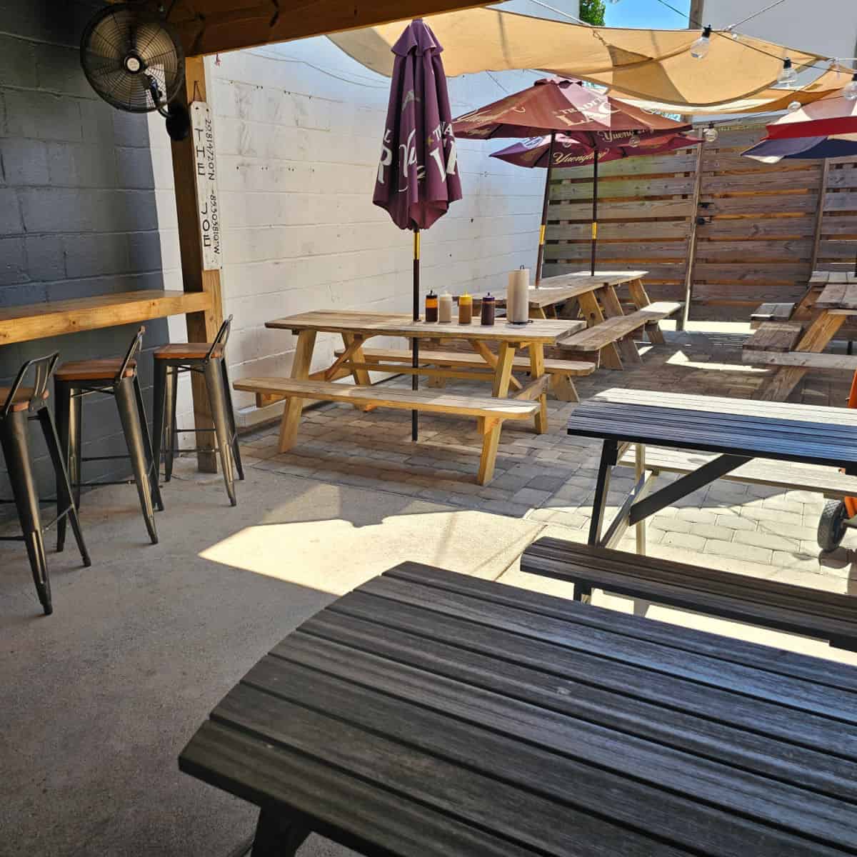 Outdoor seating at The Joe in Port St Joe with picnic tables, and tall chairs next to a counter.