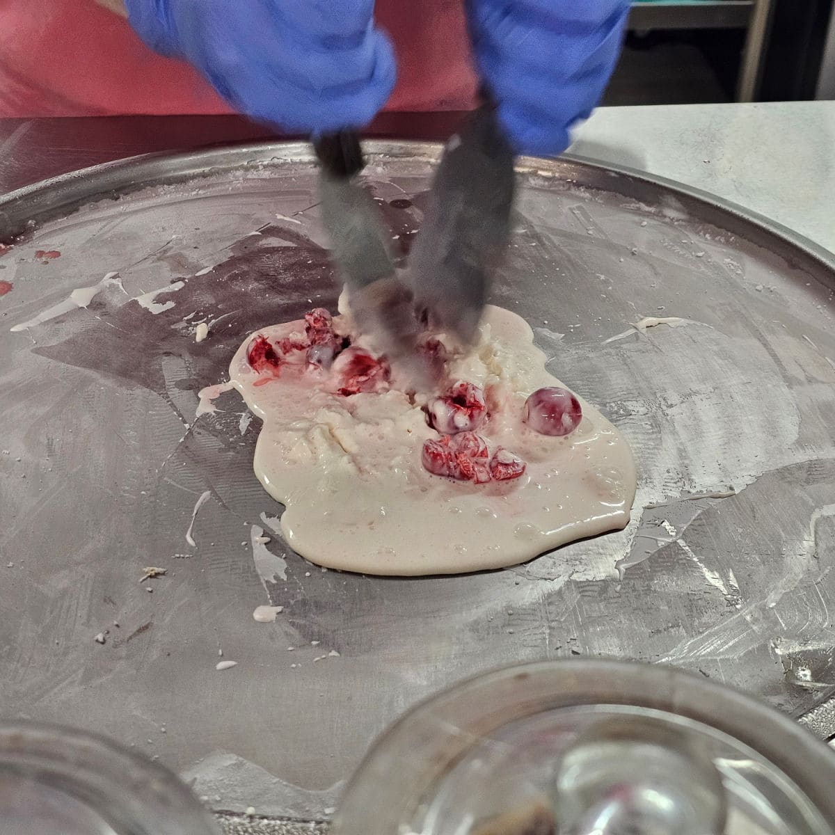 hands chopping cherries into cream on a cold plate