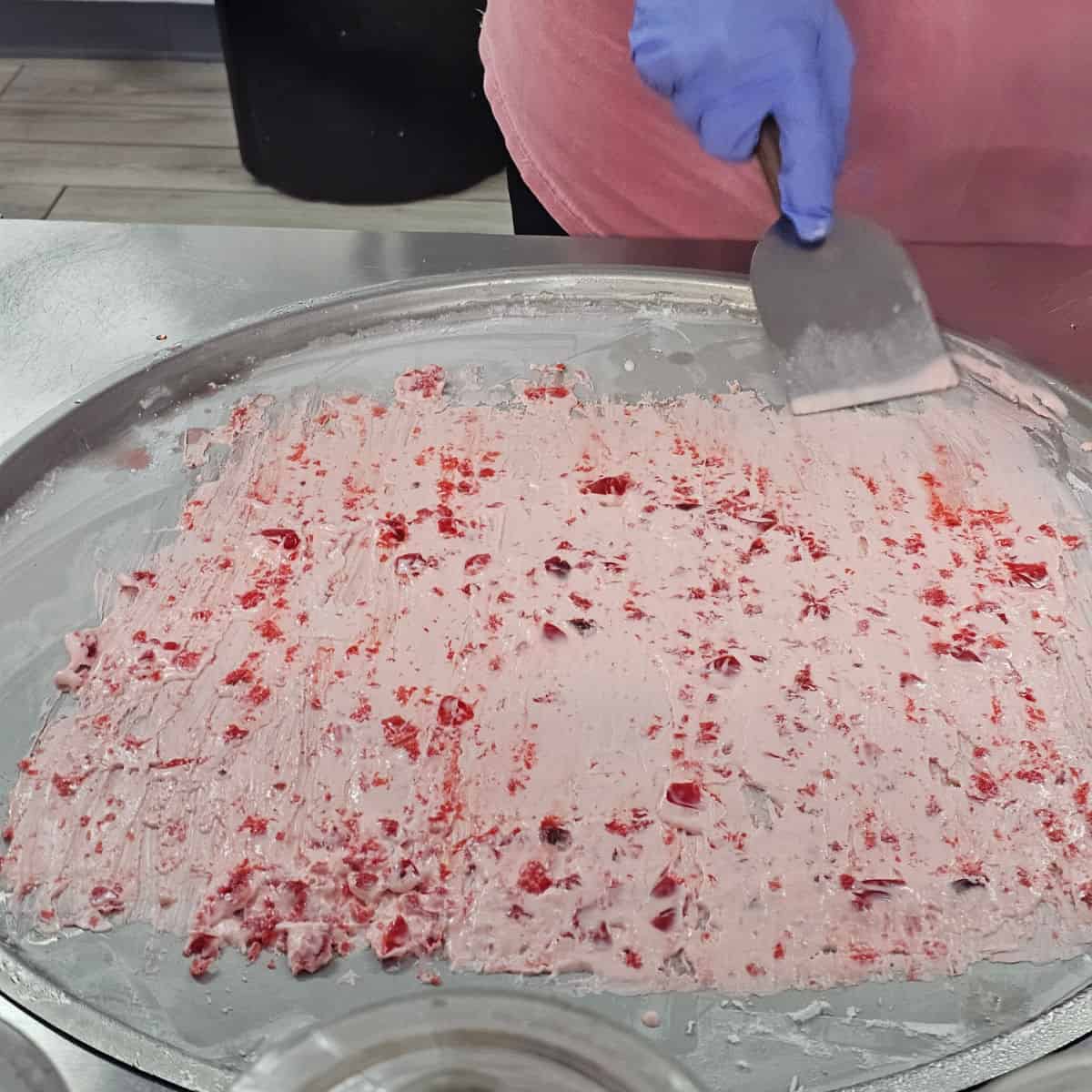 cherry ice cream spread on a cold plate with a metal spatula