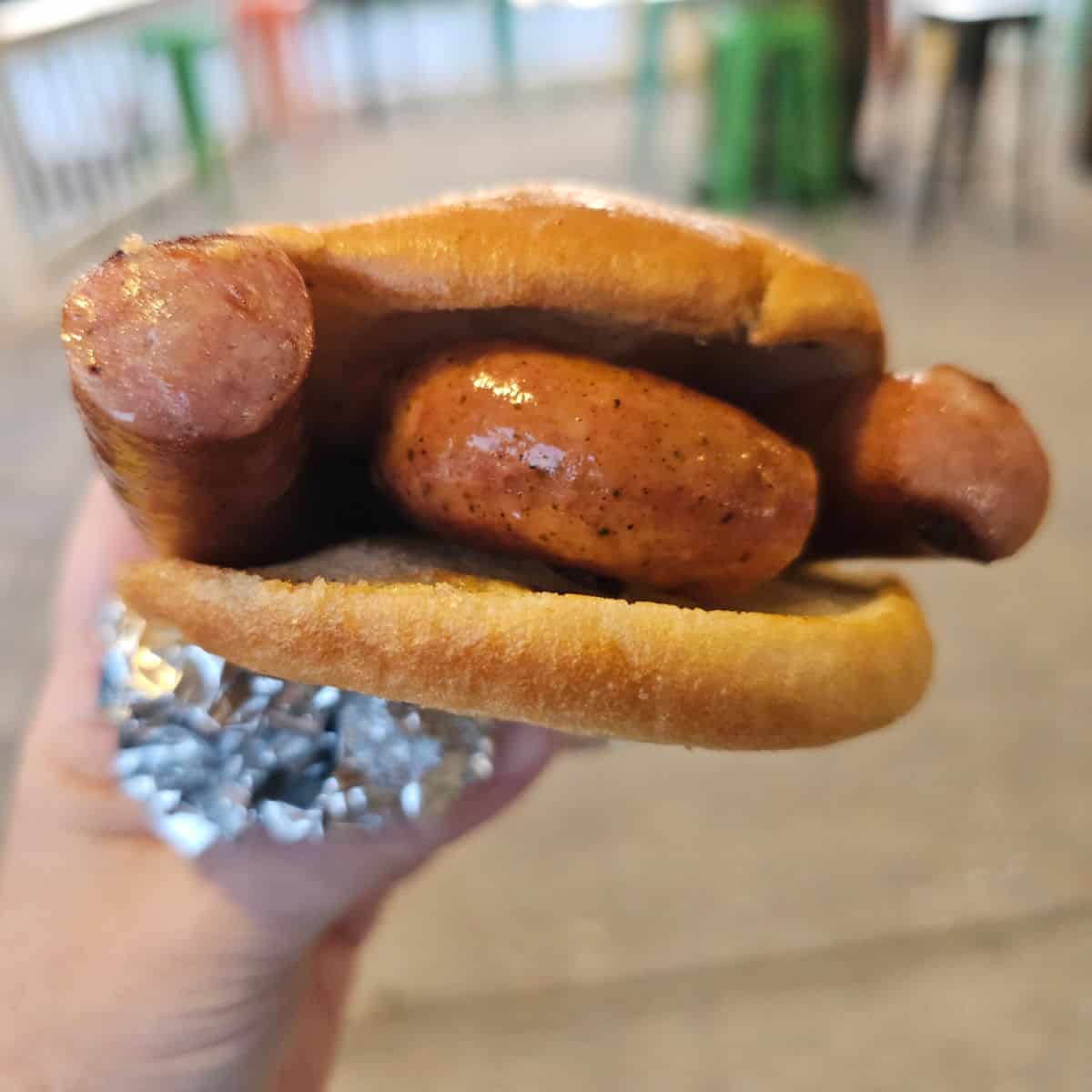 Conecuh Sausage on a bun being held by a hand