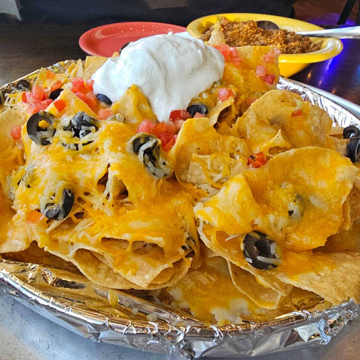 large pile of nachos with sour cream on top