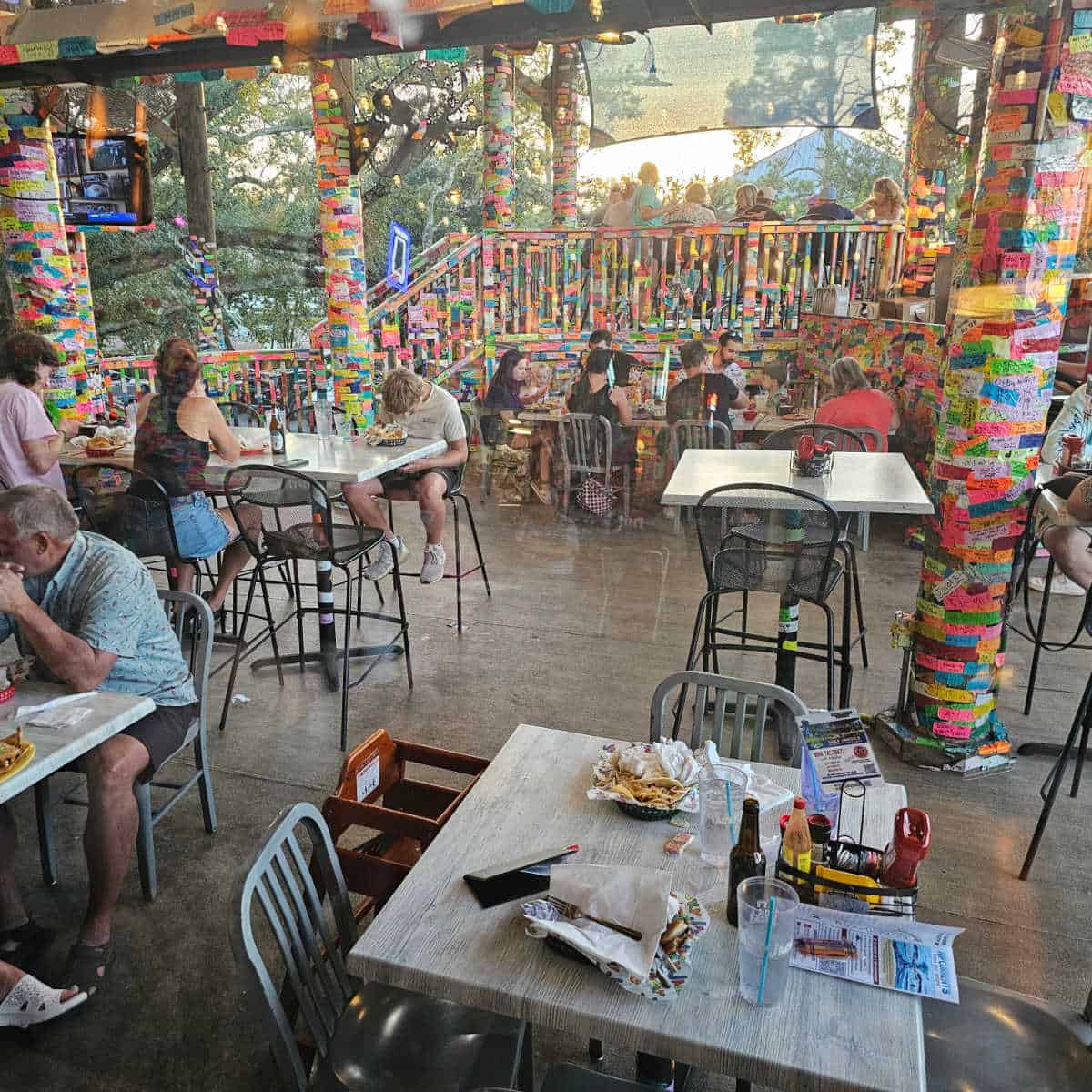 people sitting outdoors at tacky jacks with colorful tape on the pilars and ceiling
