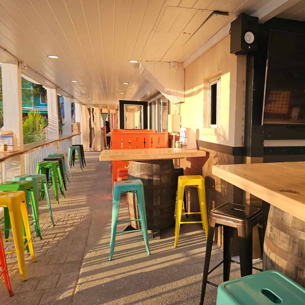 Exterior seating with colorful stools lined up along a counter and tables