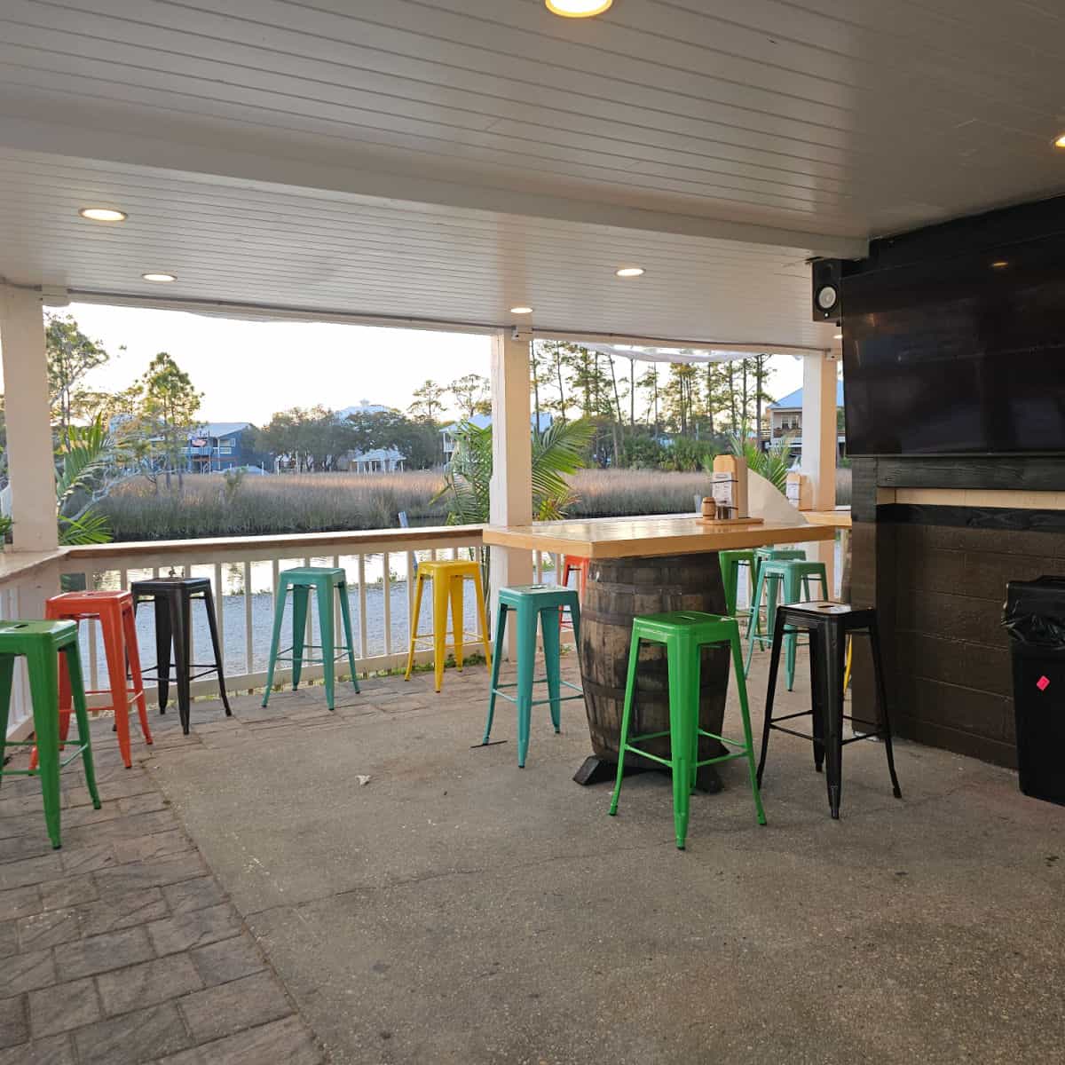 Tap & Still Exterior with colorful stools by a counter and table on a wine barrel