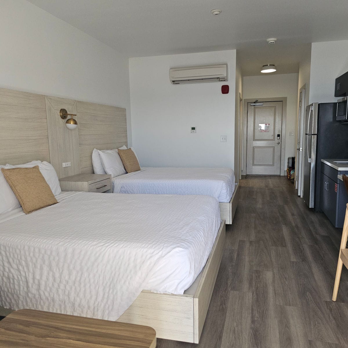 2 queen beds along one side of the Driftwood Inn hotel room, kitchenette and fridge on the other side