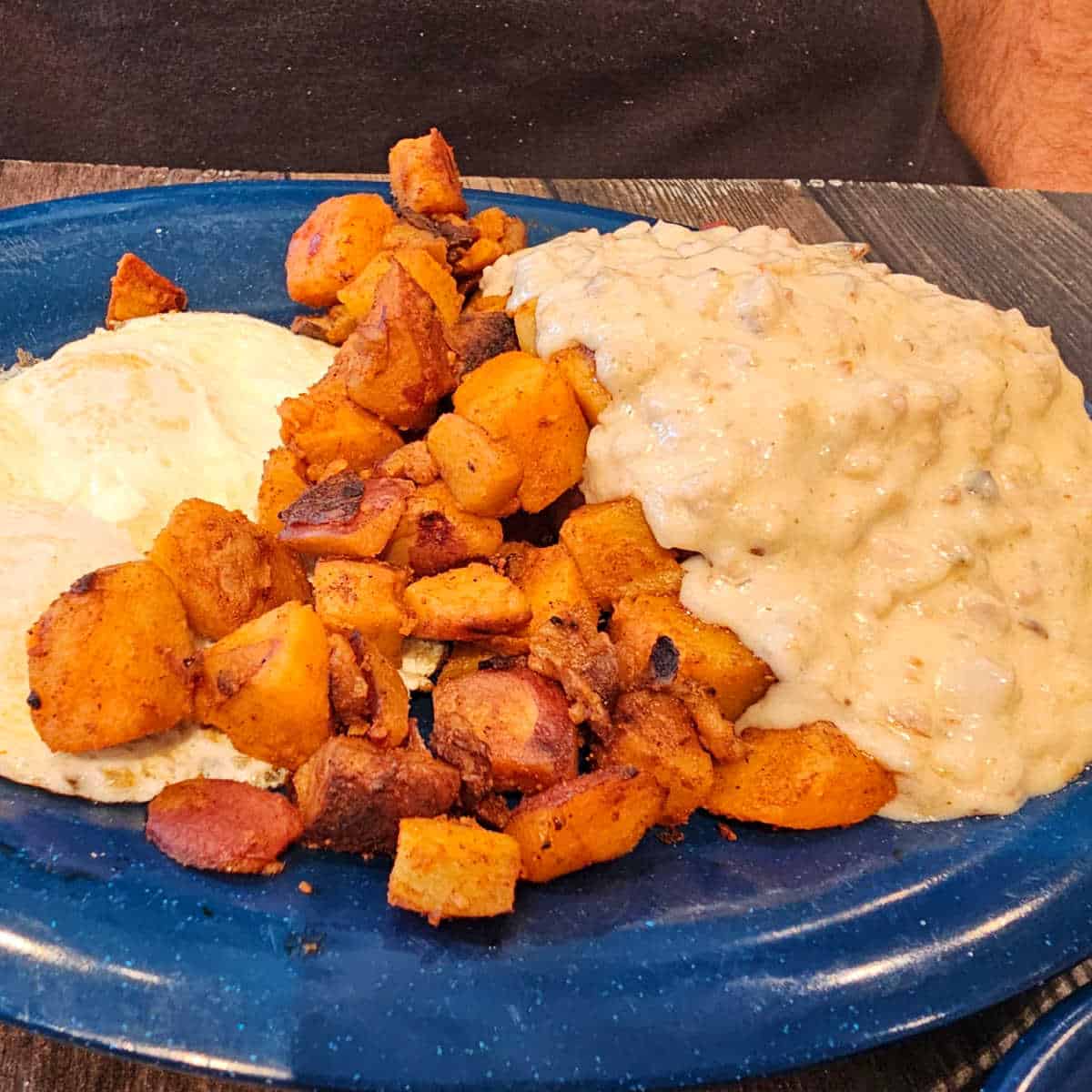 biscuits and gravy with breakfast potatoes and an over easy egg