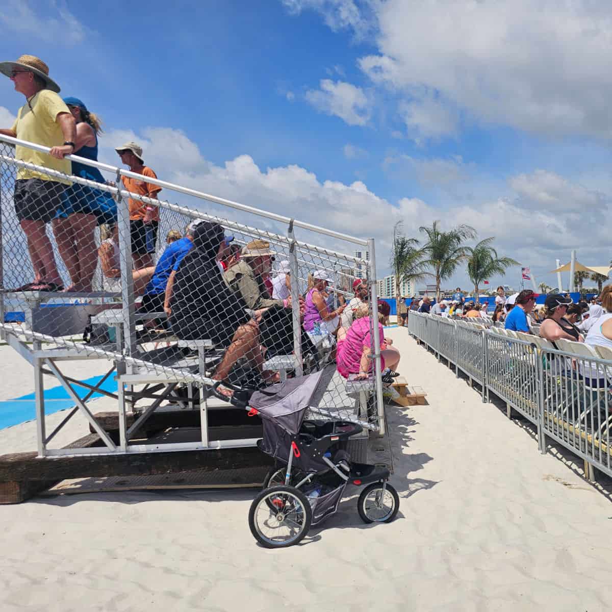 looking at the side of a set of bleachers in the sand with people sitting on the bleachers
