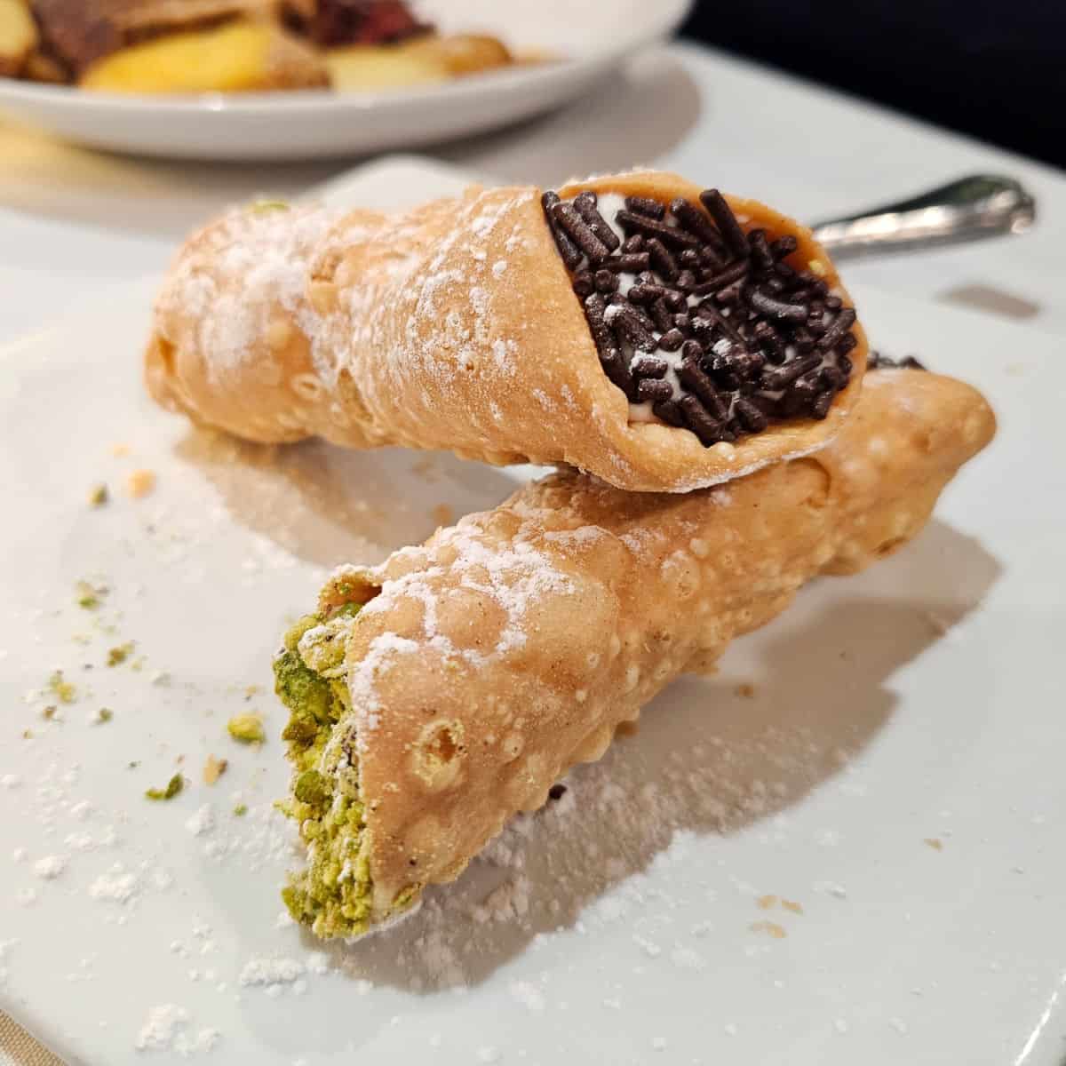 Cannolis stacked on top of each other on a white plate