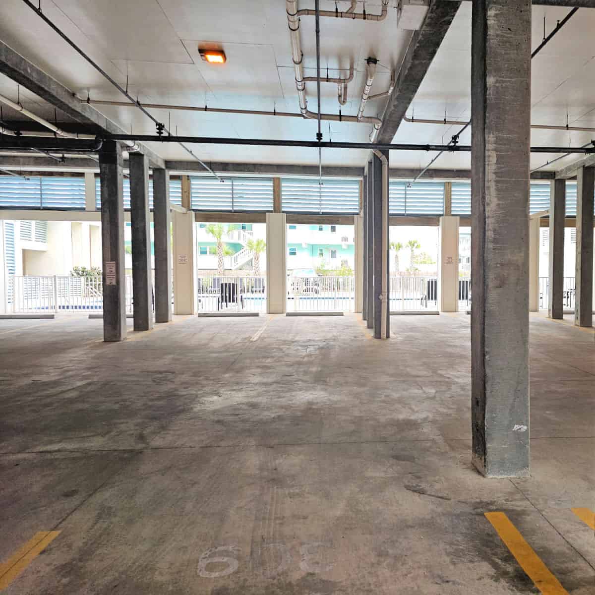 covered parking with concrete poles, looking out towards the pool area