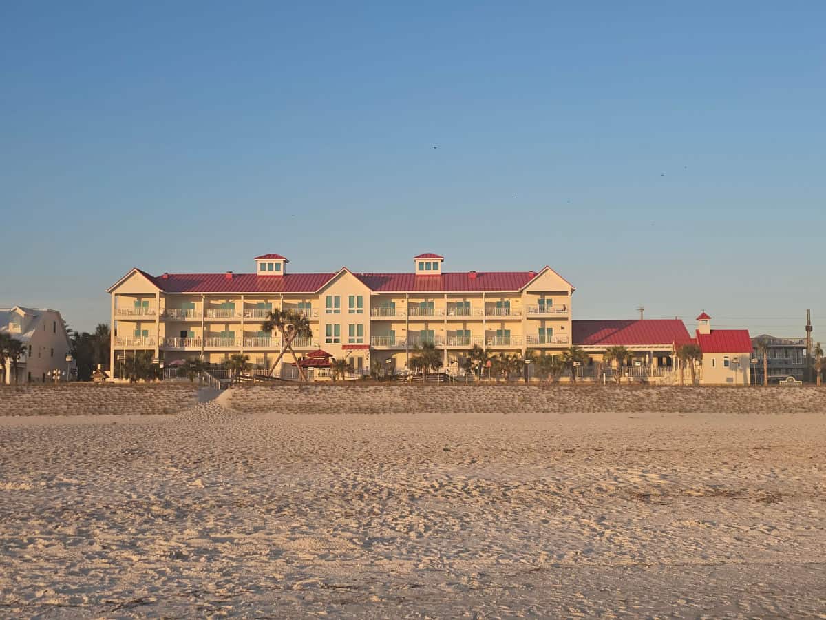 Driftwood Inn exterior seen from the sand with a red roof on a three story hotel buiding, lots of bird feeders