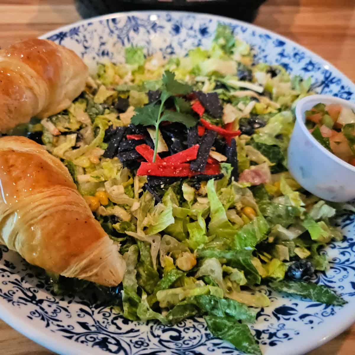 Fiesta salad with 2 croissants and a side of pico in a dish