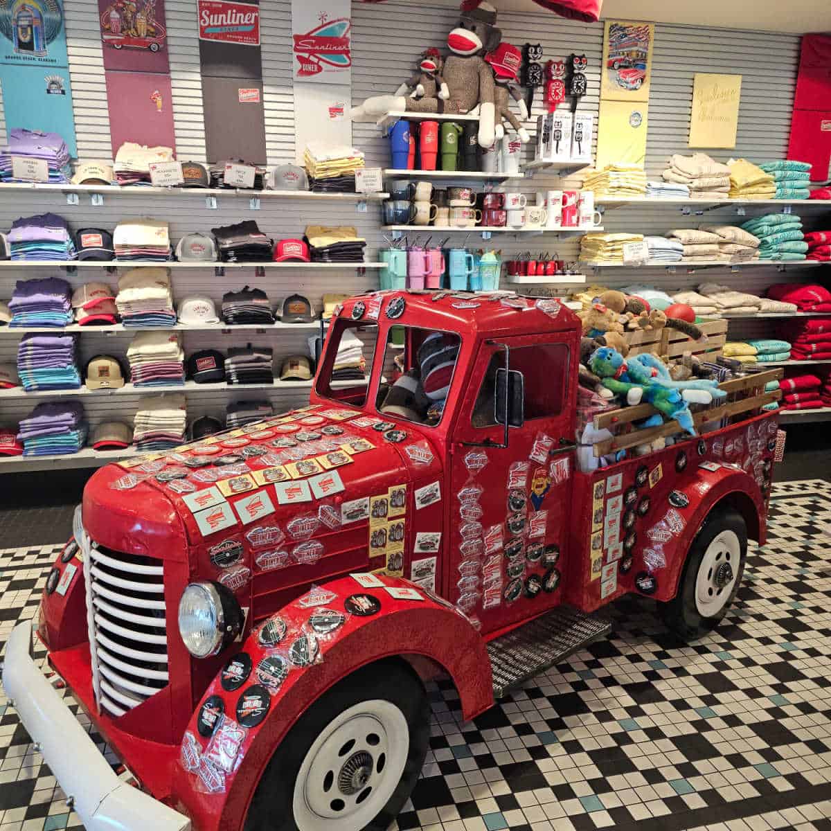 gift shop area with red truck covered in magnets, stuffed animals in the back, sunliner diner shirts on thew all with sock monkeys on a shelf