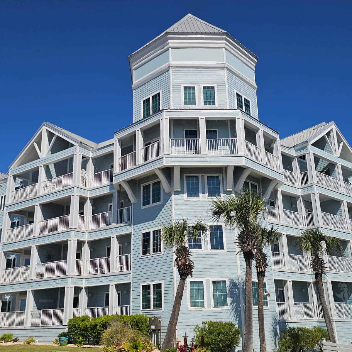 Four story Grand Caribbean building with palm trees in front of it