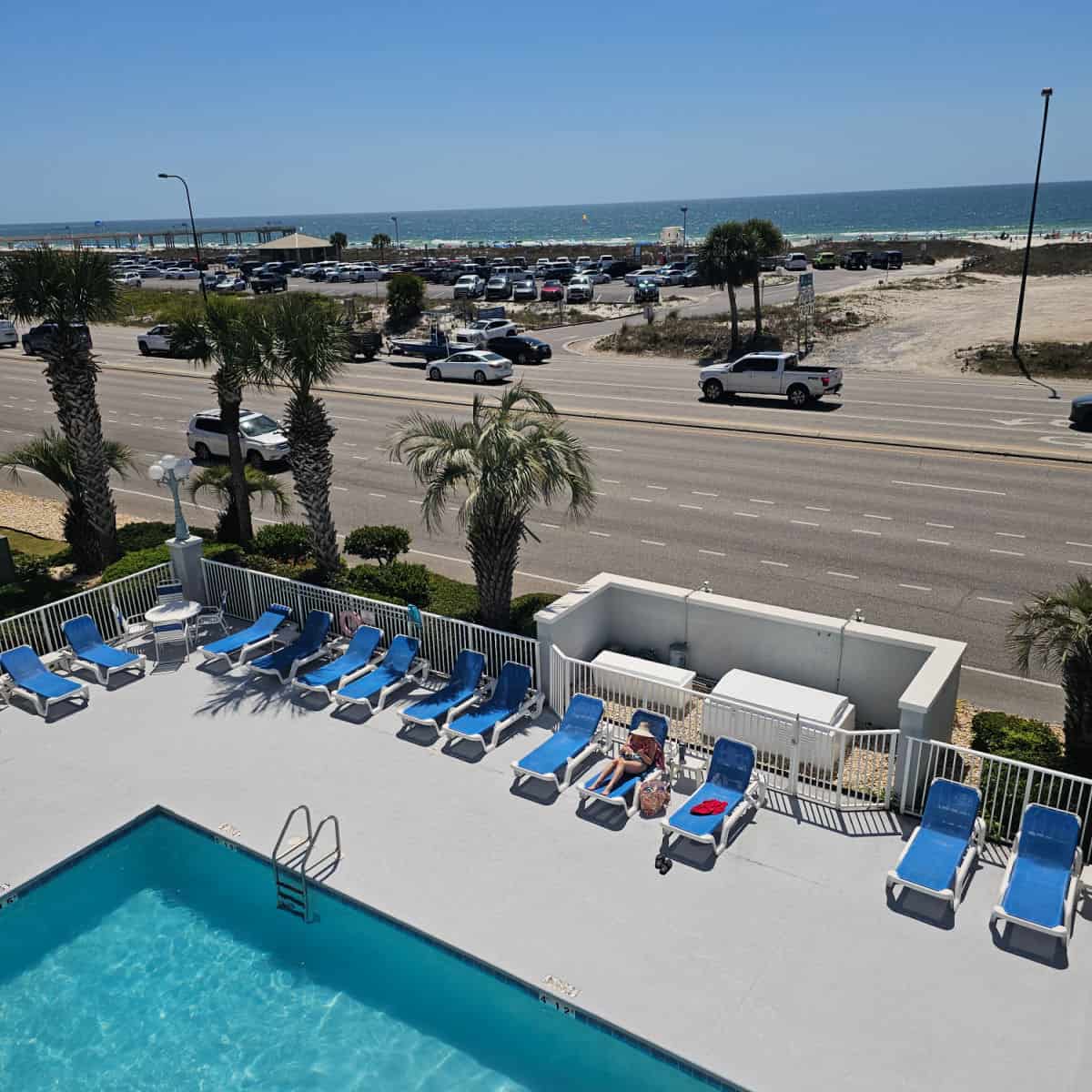 Looking over a sparkling pool to road traffic and then cotton bayou beach access and the Gulf