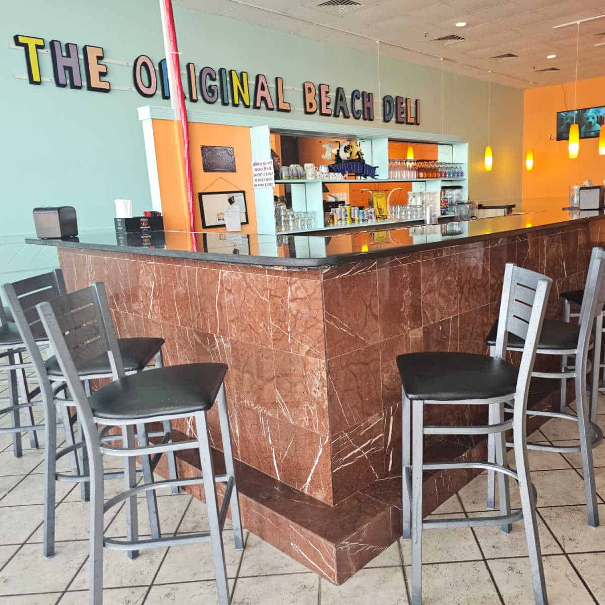 The original beli deli on the back wall above a bar area with tall chairs