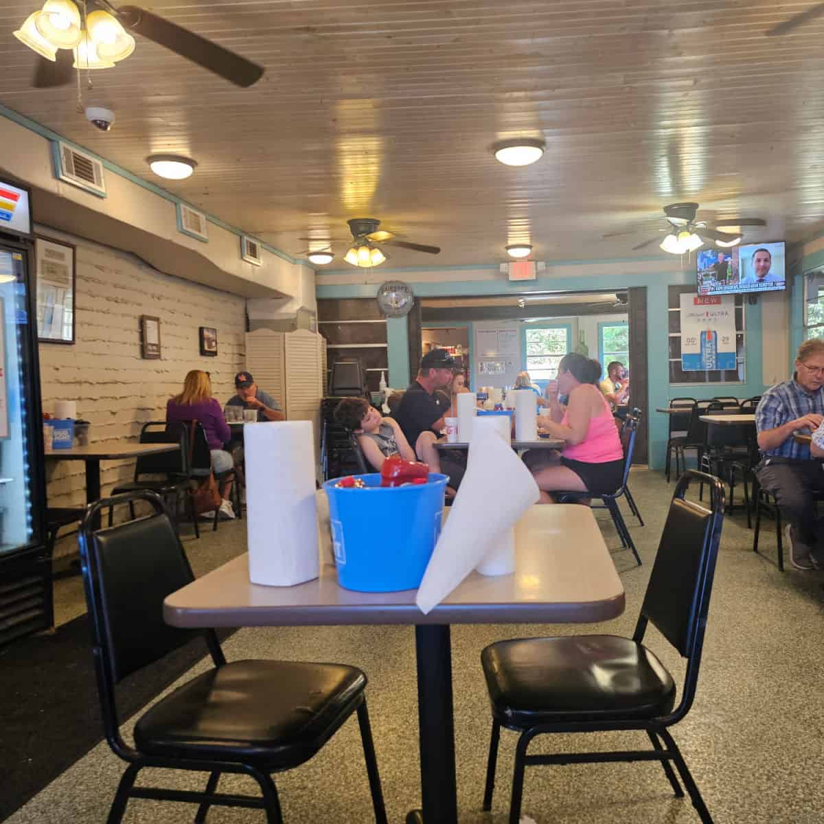 Doc's seafood shack indoor seating with tables and chairs, people sitting having lunch, tv on the back wall
