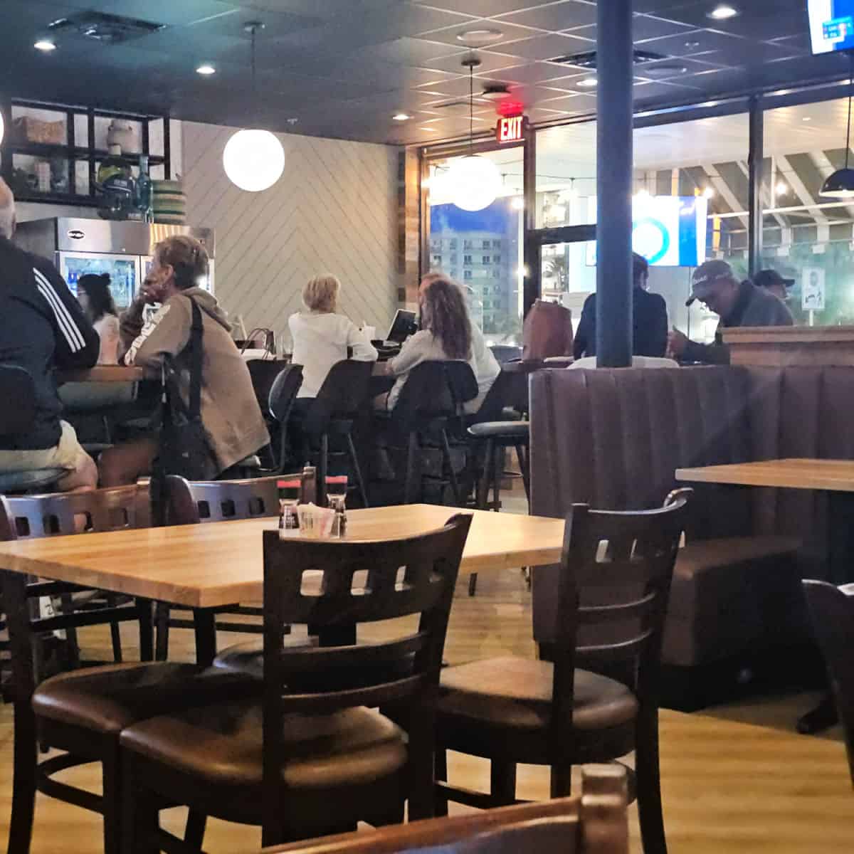 Old Salt Tavern interior seating with tables and chairs, booths, and people sitting along a bar area