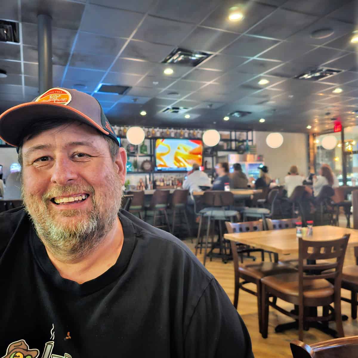 John at Old Salt Tavern with bar behind him and tvs on the wall